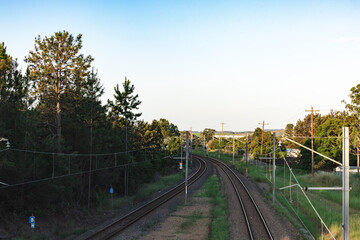 Train tracks going around a bend surrounded by power lines