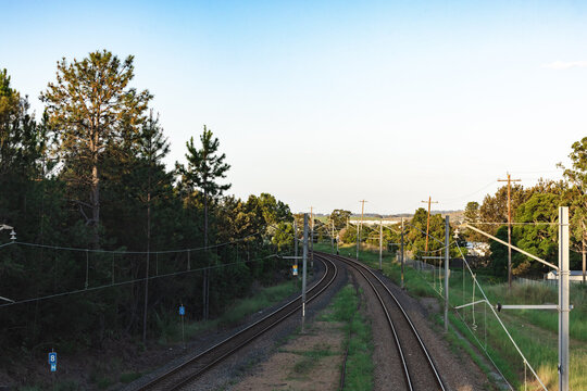 Train tracks going around a bend surrounded by power lines