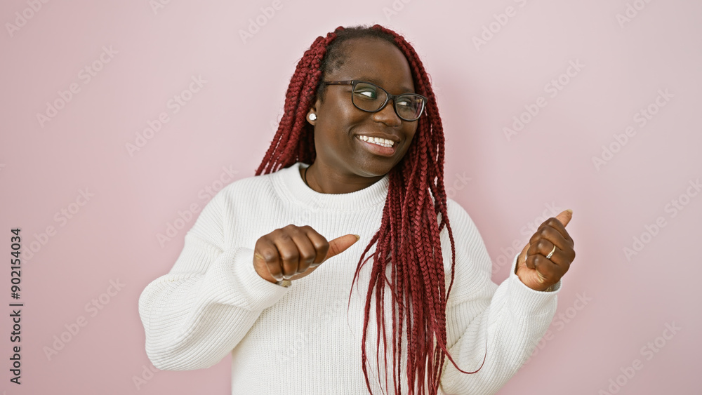 Poster a cheerful black woman with braids pointing sideways over an isolated pink background exudes confide