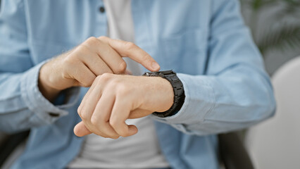 A professional man checks the time on his wristwatch in an office setting, conveying punctuality...