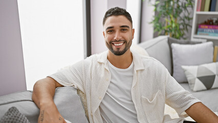 Handsome bearded man relaxing indoors in a stylish living room, exuding casual elegance and comfort.