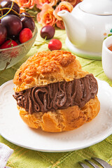 Profiteroles with chocolate cream on white plate .  