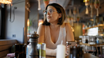 Young beautiful hispanic woman smiling sitting on the table at the restaurant