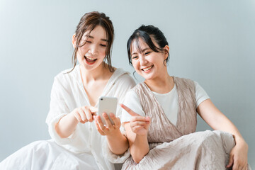 家で一緒にスマホを使う女性・友達・ママ友・仲間
