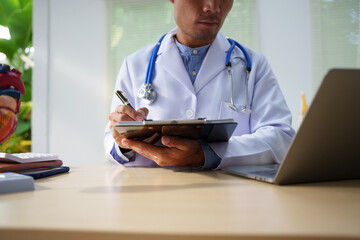 A medical doctor is working at a desk, analyzing patient data related to heart attacks and calculating medical costs to ensure accurate billing and financial management in the healthcare setting.