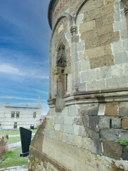 Ancient stone mausoleum with intricate carvings against a blue sky, showcasing historical...