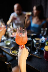 Close up of people drinking cocktails in restaurant. People having good time, cheering and drinking cold cocktails, enjoying friendship together in restaurant, close up view on hands.