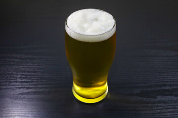 Glass of Beer with Foam on Black Table