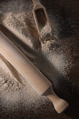 Pile of flour, rolling pin and scoop on wooden table, flat lay