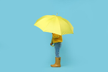 Little girl with yellow umbrella on light blue background