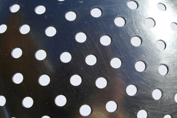 Close-up of a metallic slotted spoon with multiple round holes