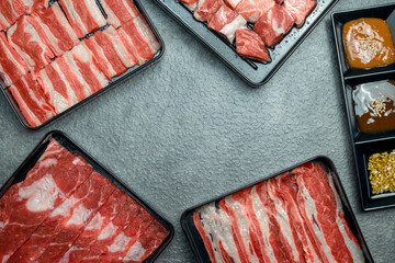 A variety of meats are displayed in plastic containers on a grey surface