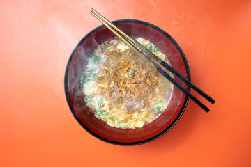 A bowl of instant noodles and vegetables with chopsticks in it
