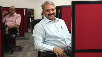 Happy mature indian employee or bank manager working in office, Smiling mid aged senior corporate person looking at camera.