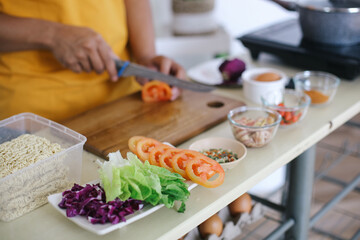 Man Cutting Tomato and Ingredients For Making Meals On The Kitchen Table