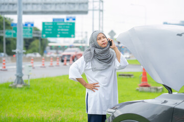 The car has a problem, Asian Muslim women encountered a problem with the car driving the broken machine, opening the hood, checking the car, looking for the cause of the broken car.