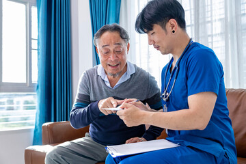 Obraz premium Senior elder man got service visit from male caregiver nurse at home while having result of body temperature from thermometer medical exam for health care and pension welfare insurance
