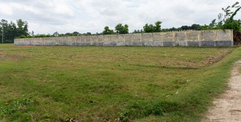 Big wall behind the green field and the sky behind it