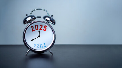 2024 and 2025 on white alarm clock on black table with copy space for preparation of Merry...