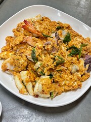 Omelette with shrimp and seafood on rice and sauce on white ceramic plate and spoon and fork.Omelette with shrimp and seafood on rice and sauce on white ceramic plate and spoon and fork.