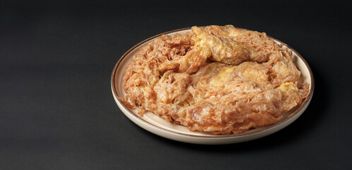 Thai-style pork omelette on black background with copy space.