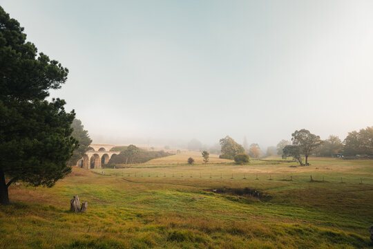 Foggy morning in the valley with historic bridge
