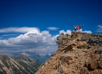Group of friends hikers on mountain top against blue sky and clouds. Colorado. USA