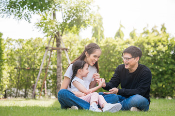 Happy Asian family mother, father and daughter having fun playing outside their home in garden