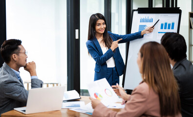 Confident Asian businesswoman with financial or marketing graph charts on a board to presentation, Business training meeting concept.