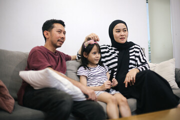 Happy Asian Family Watching TV Together On Sofa In Living Room At Home