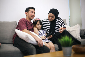 Fototapeta premium Happy Asian Family Watching TV Together On Sofa In Living Room At Home