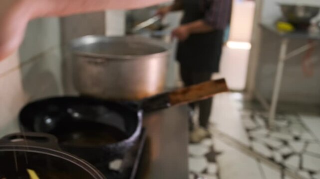 Close-up of adding zira seasoning with the hand of the chef sprinkles on chopped vegetables while preparing real Uzbek pilaf in cauldron.
