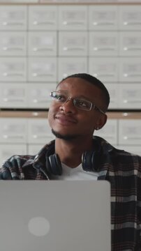 Woman fixes hair near groupmate with laptop. Female student talks to black guy sitting at table in classroom. Interesting lecture during education