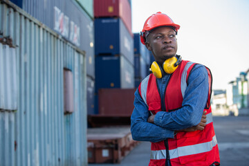 portrait of Male African American smiling engineering in uniform wear hard hat standing containers yard. Area logistics import export and shipping.