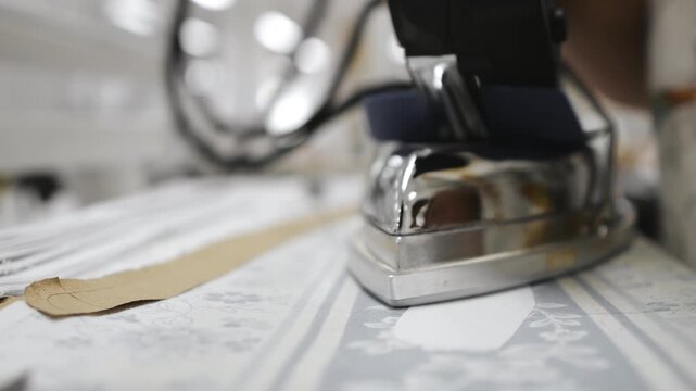 Factory for the production of clothing. A seamstress smoothes a piece of textile with an iron. Close-up of a seamstress's hands with an iron.