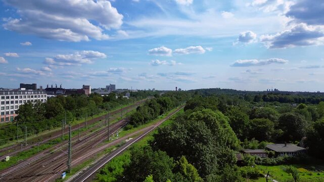 Railroad line parallel to the park with path on a sunny summer day. Fabulous aerial view flight rotation to right drone