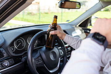 A drunken man driving a car with a bottle of alcohol in his hand. Close-up of a bottle of Alcohol...