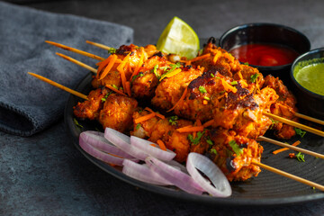 Deliciously Spiced Chicken Tikka Kabab, A Flavourful Grilled Delight with Tangy Marinade and Smoky Charcoal Aroma Serve with Mint and Tomato Chutney. Selective focus. 