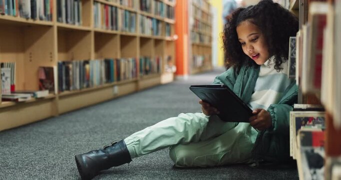 Tablet, child and student in library for learning, education or reading info for knowledge. Technology, girl and kid at school for studying with ebook, internet course or math lesson online on floor
