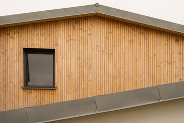 Modern architecture gable with flat roof made of metal titanium zinc and cladding made of untreated natural larch wood