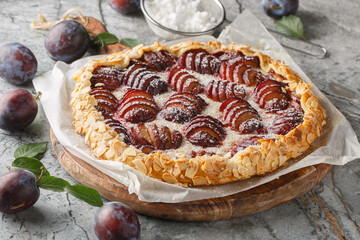 Freshly baked plum fruit pie with almonds close-up on a wooden board on the table. Horizontal