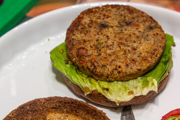 Hamburguesa vegana de trigo sarraceno colocada sobre un panecillo con una hoja de lechuga. Un plato vegano simple y saludable que combina una hamburguesa nutritiva y lechuga fresca en un panecillo int