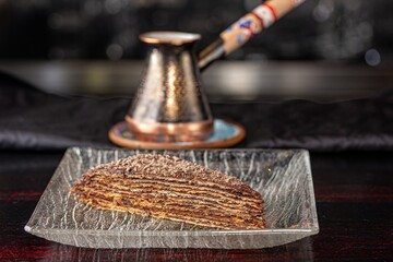 Cafetera tradicional con un trozo de pastel en un plato de cristal.