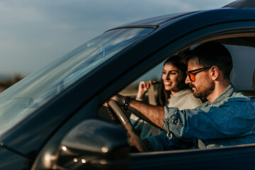 Focused man starting the car, woman putting a seat belt