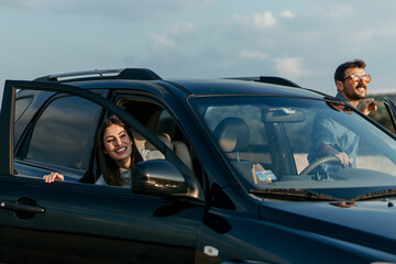 Loving urban styled couple getting out of the car, ready to enjoy sunset in the nature