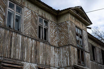 An old abandoned wooden house with damaged windows and a crumbling roof
