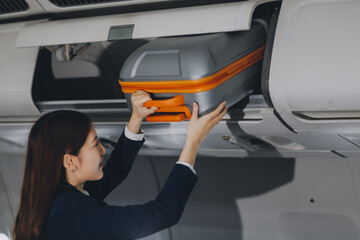 Female tourist packing her luggage in the airplane cabin.