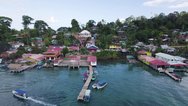 Aerial view of a colorful village on stilts, showing boats navigating the turquoise waters of bastimentos island