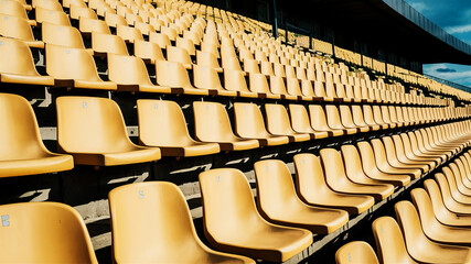 Fototapeta premium Endless rows of empty blue plastic seats await unseen audience in vast outdoor arena
