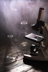 Vintage Laboratory Equipment: Microscope and Flasks in Ambient Light with Smoky Background